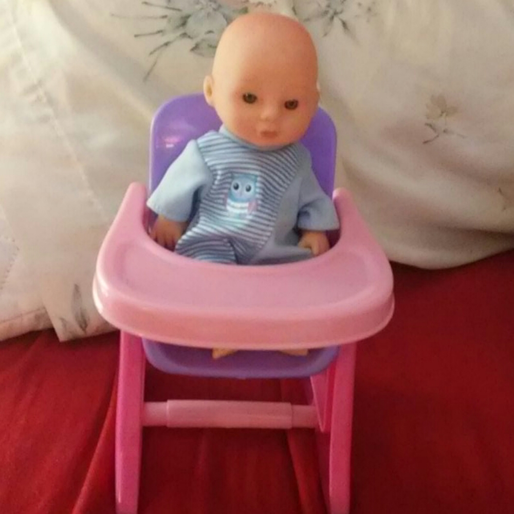 A baby doll with a hight chair